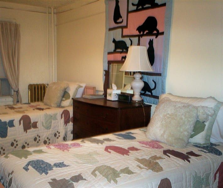 A bedroom with two beds and a lamp with cats on the wall