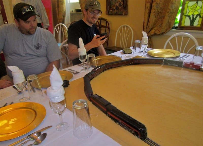 Two men are sitting at a table with a train on it
