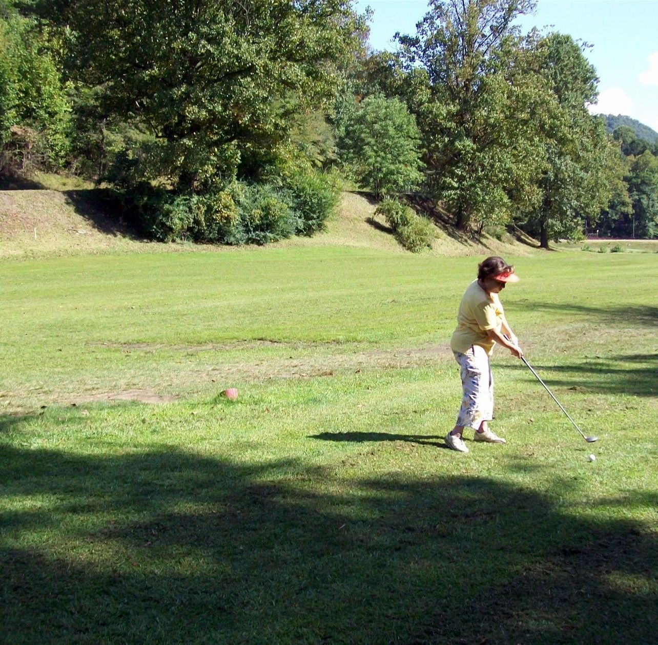 A woman is swinging a golf club in a grassy field