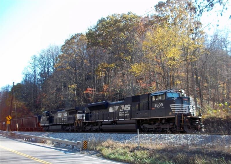 A train is going down the tracks next to a road.