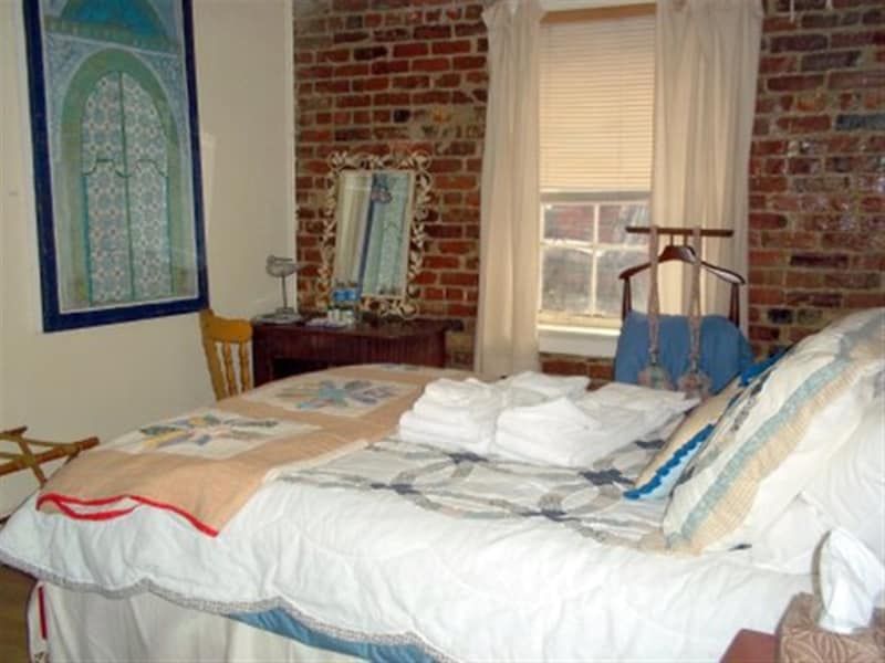A bedroom with a brick wall and a large bed