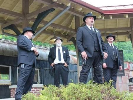 A group of men in suits and hats are standing in front of a building.