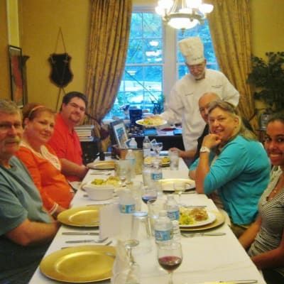 A group of people are sitting at a long table with plates and glasses of wine