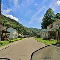 A person is riding a motorcycle down a street in a small town.