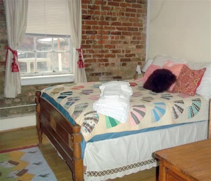 A bedroom with a bed and a window with a brick wall