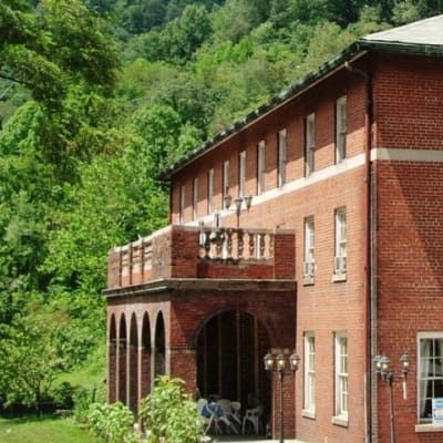 A large brick building with a balcony is surrounded by trees