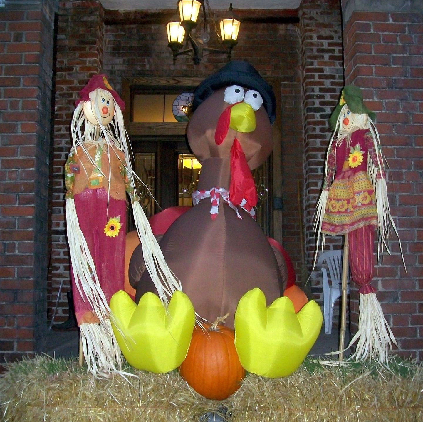 A large stuffed turkey is surrounded by scarecrows and a pumpkin