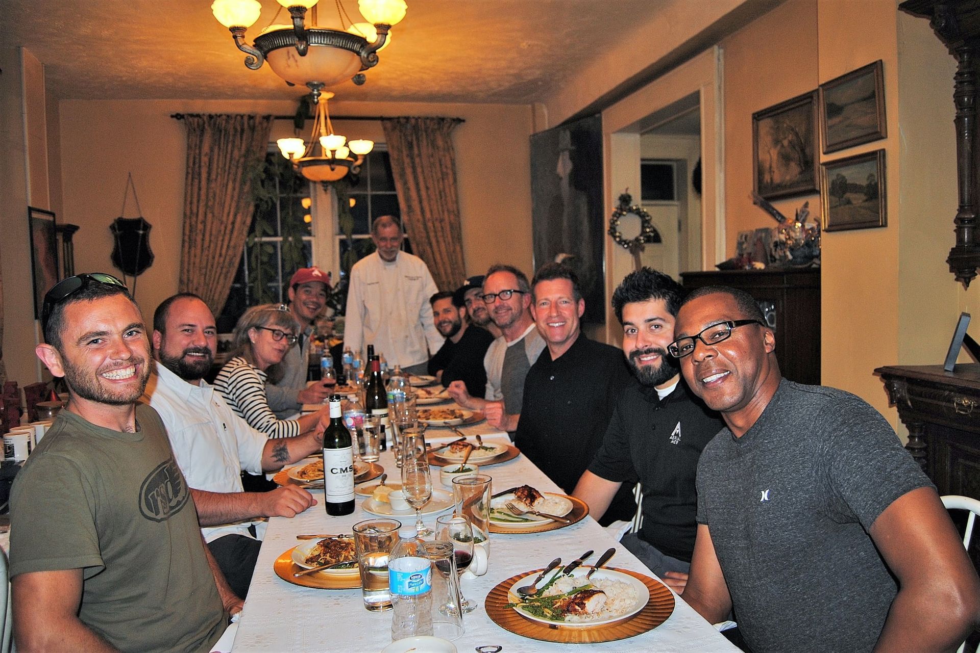 A group of men are sitting at a long table with plates of food.