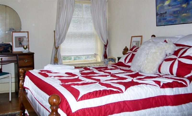 A bed with a red and white quilt in a bedroom