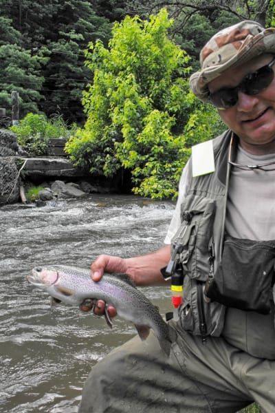 A man is holding a fish in front of a river