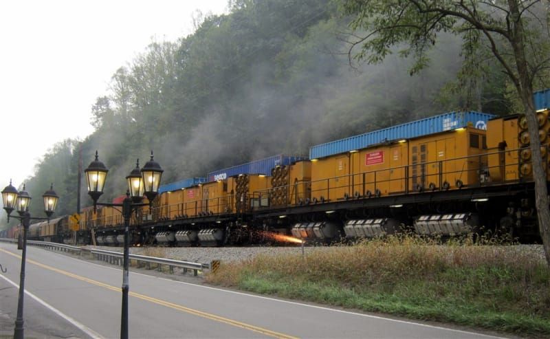A train is going down the tracks next to a road.