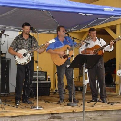 Three men playing guitars and a banjo on a stage