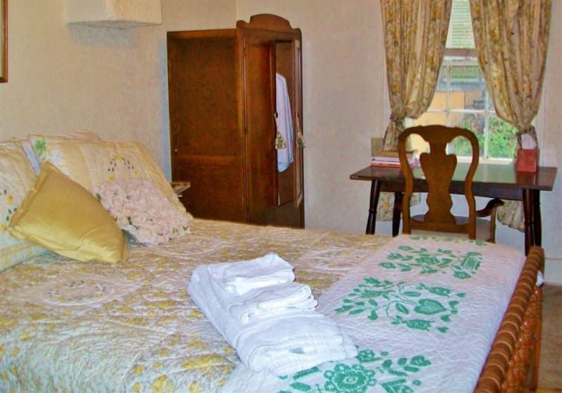 A bedroom with a bed a desk and a window