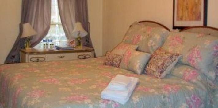 A bedroom with a bed , dresser , and window.