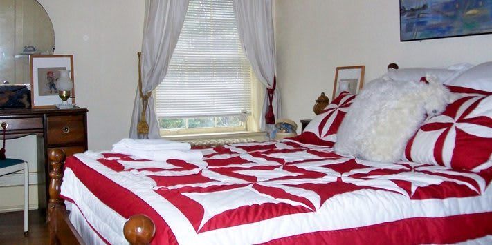 A bedroom with a bed with a red and white quilt