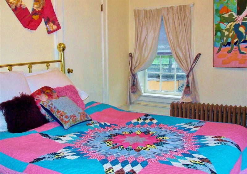 A bed with a pink and blue quilt on it
