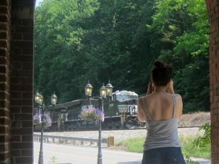 A woman is taking a picture of a train through a window.