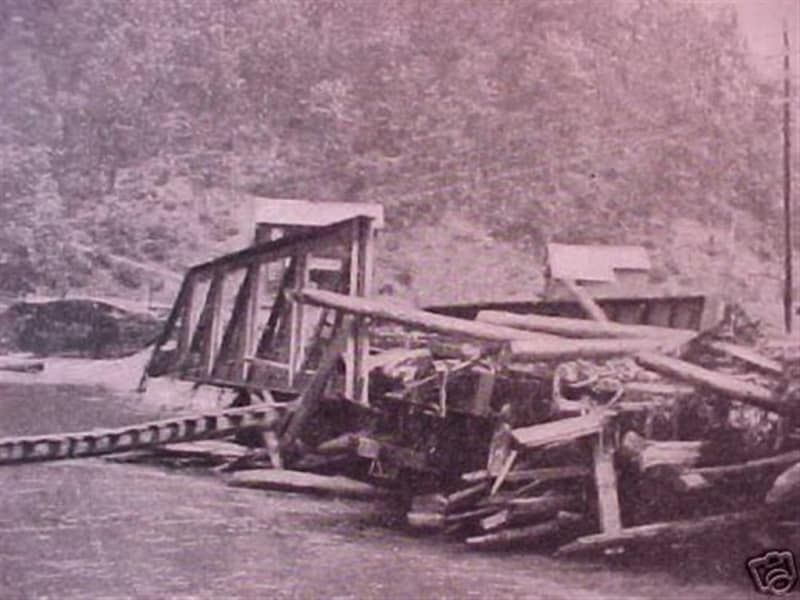 A black and white photo of a bridge being demolished
