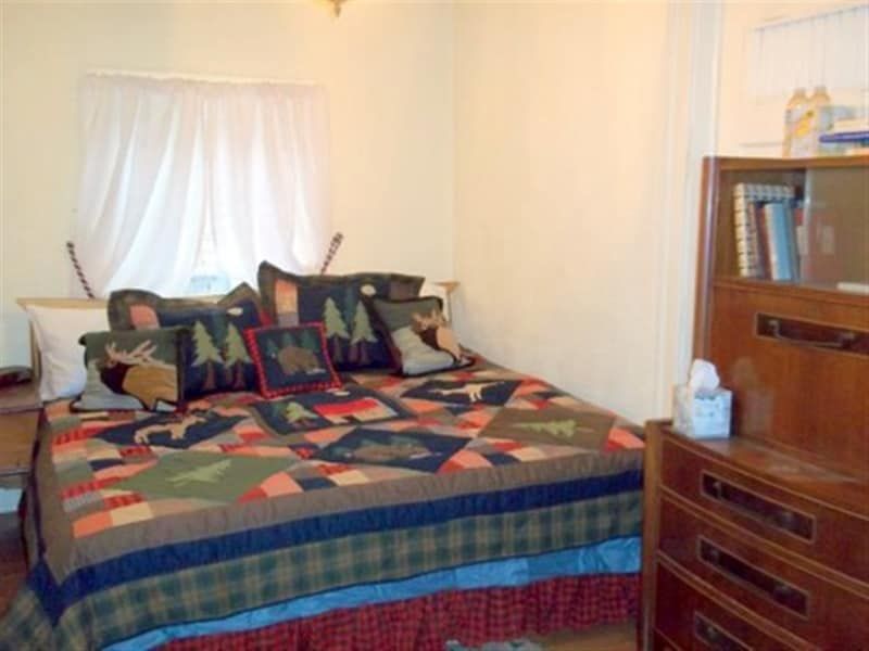 A bedroom with a bed and dresser and a window