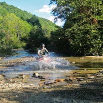 A man is riding an atv through a river.