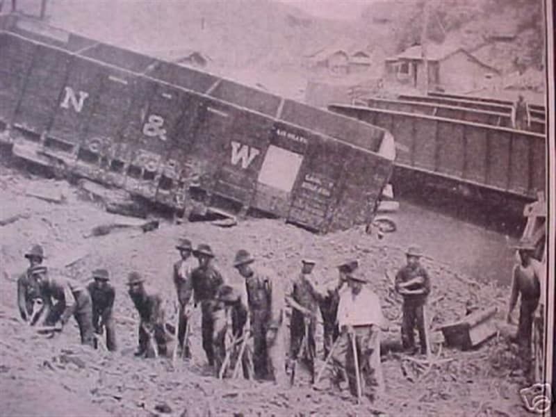 A group of men are standing in front of a train car that has the letters n and w on it