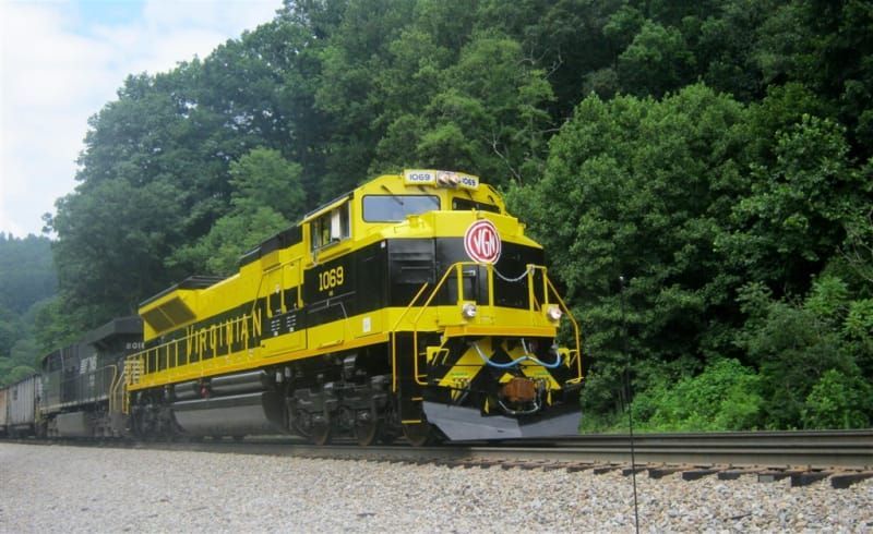 A yellow and black train is going down the tracks.