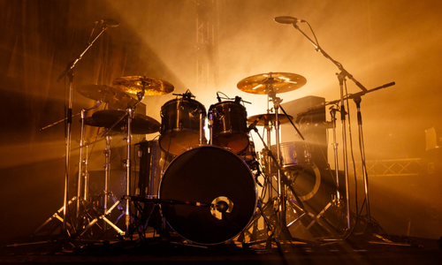 Concert crowd silhouetted against bright stage lights. People hold up phones, enjoying a music performance.