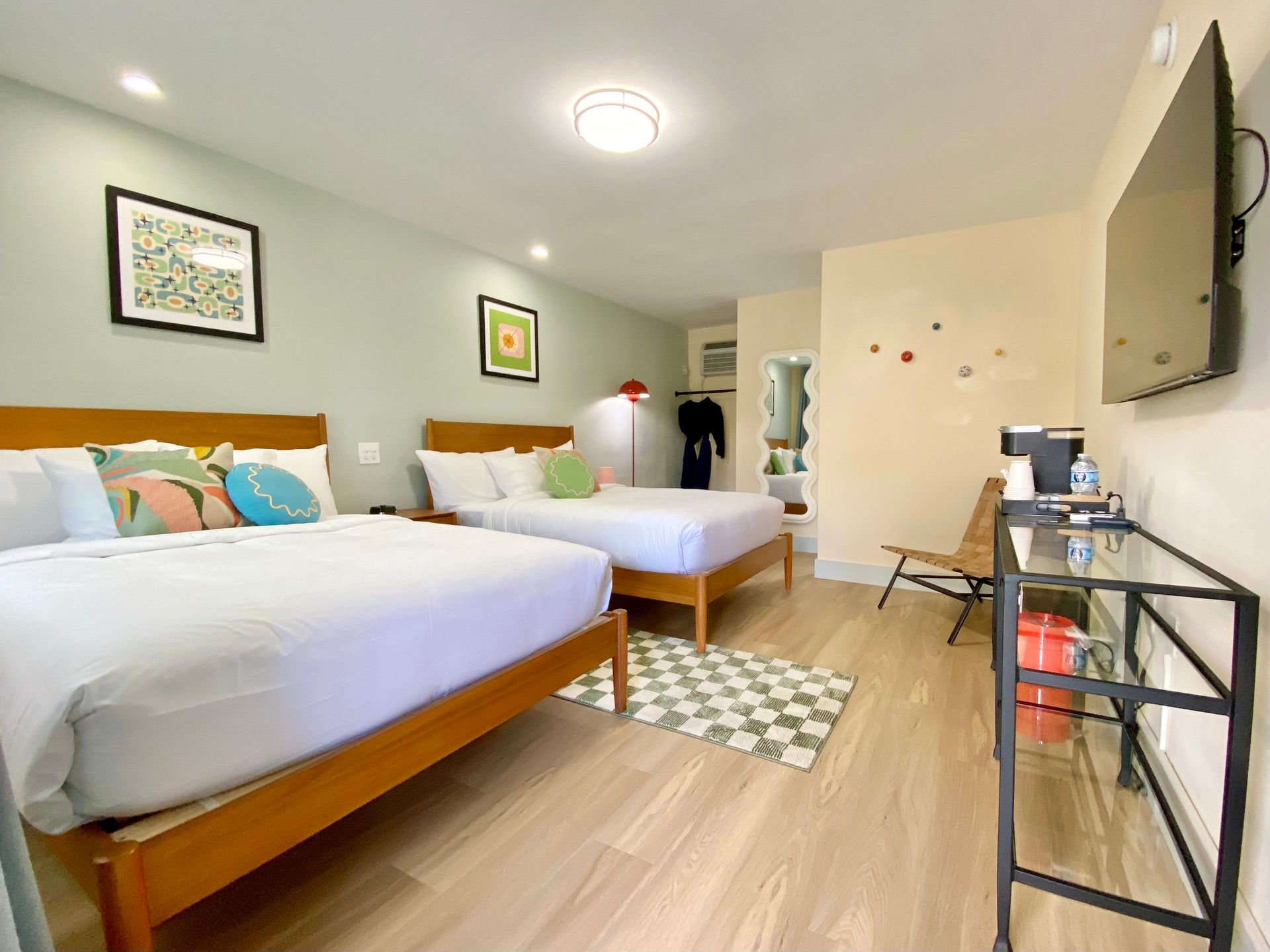 Bedroom with two twin beds, art, and pastel walls. Includes a chair, rug, and bedside tables.