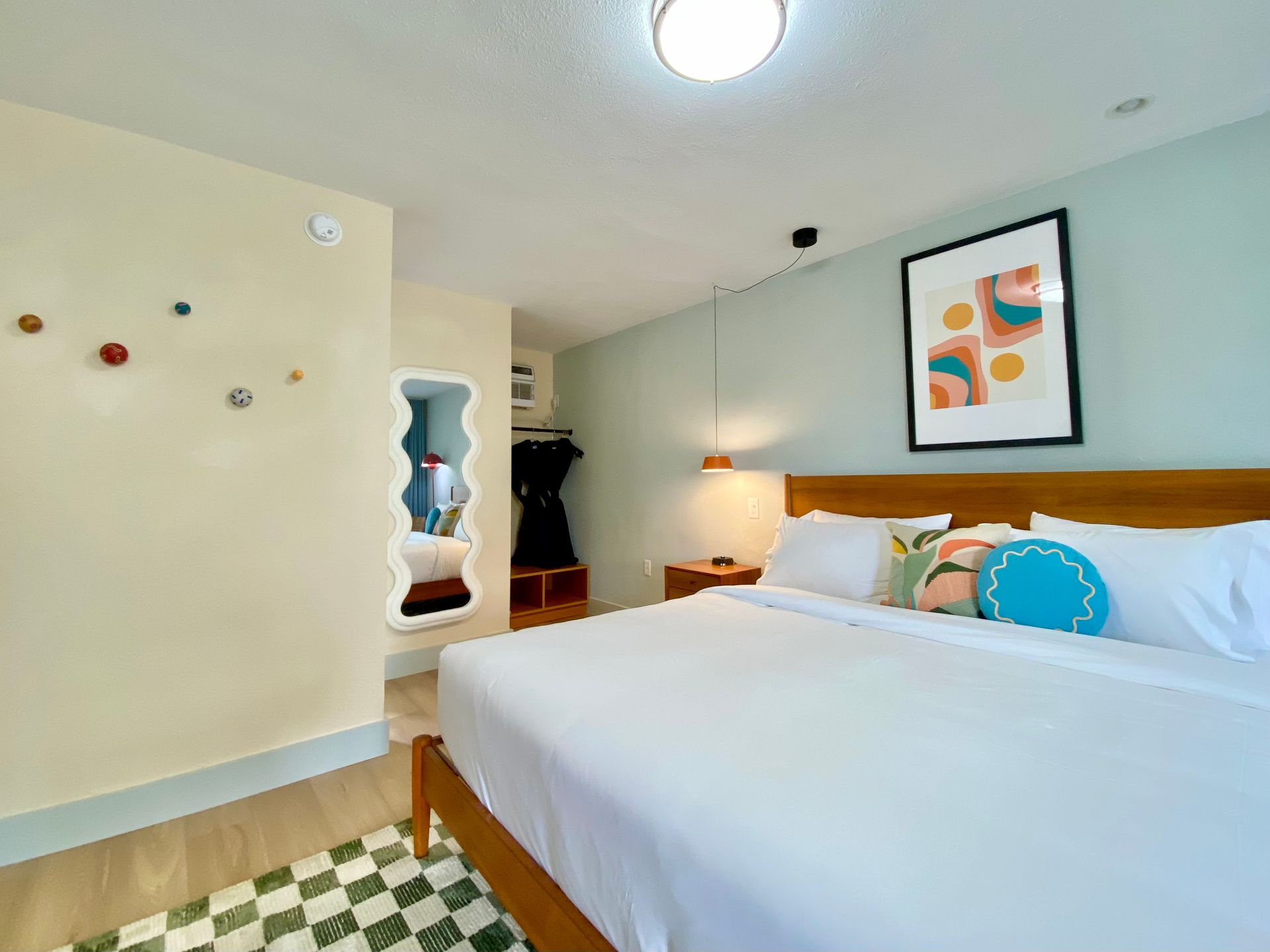 Bedroom with light wood furniture, mint and yellow walls, and a checkered rug.