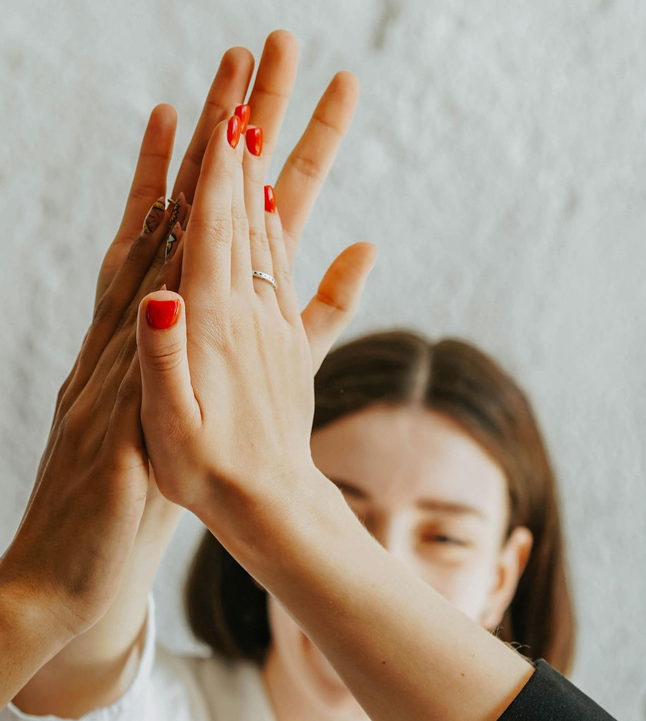 A woman with red nails is giving another woman a high five