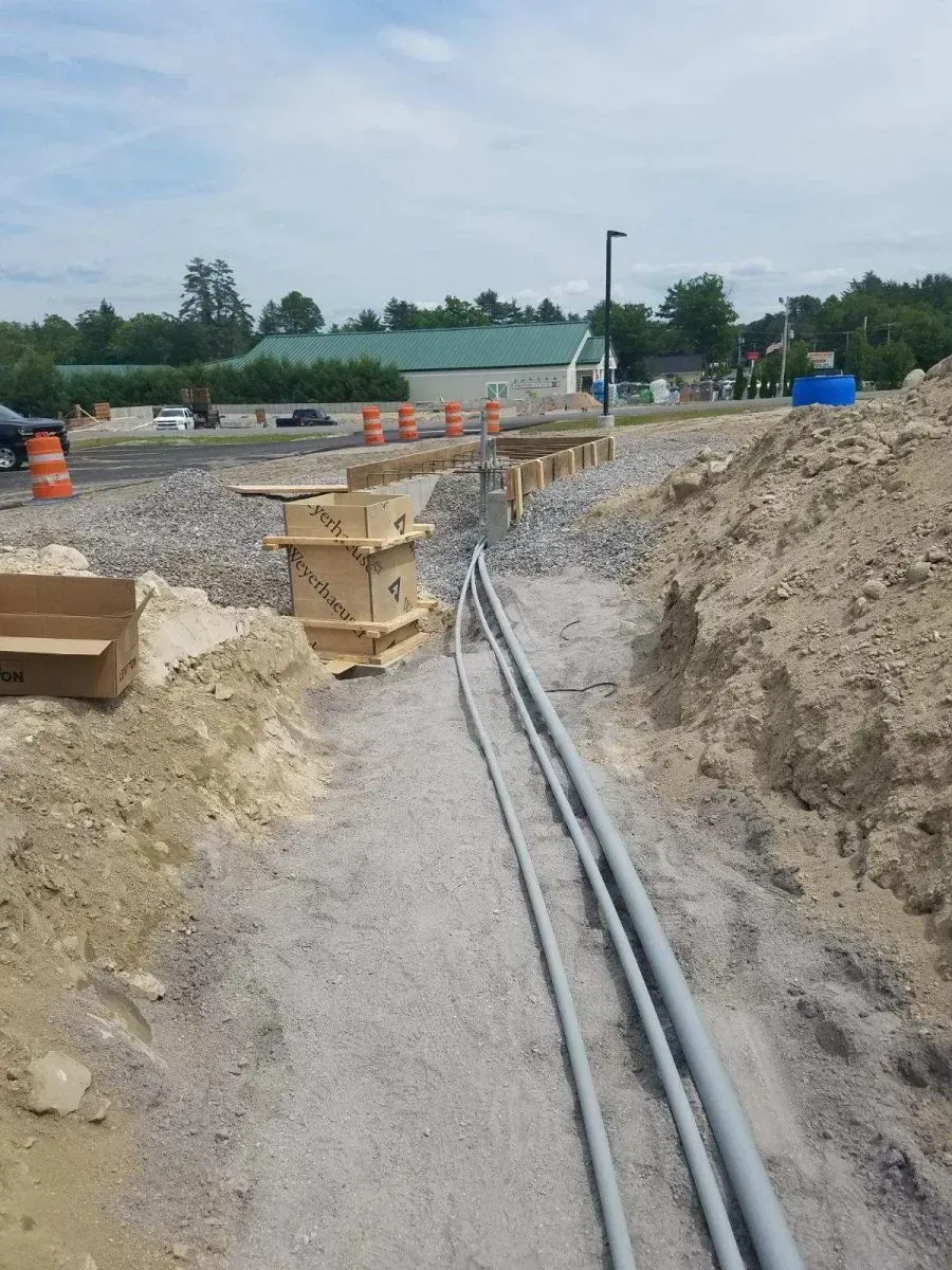 A bunch of pipes are laying in the dirt on a construction site.