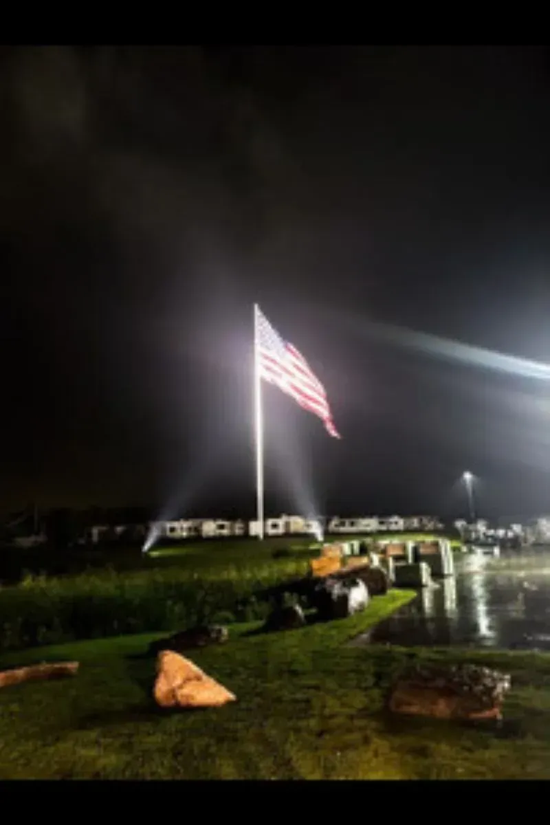 An american flag is flying in the wind at night
