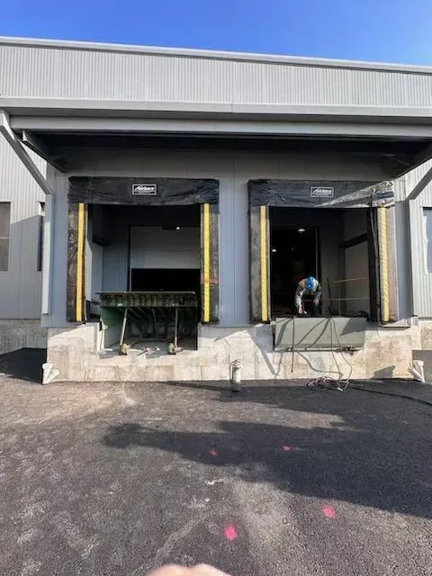 A person is standing in front of a building with a loading dock.
