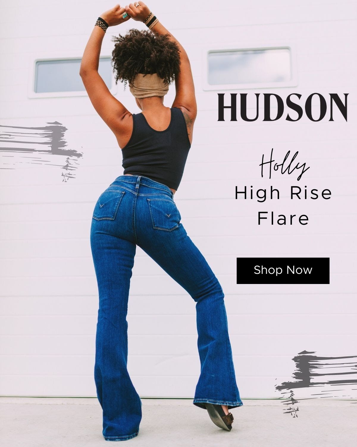 A woman in a black tank top and blue jeans is standing in front of a white garage door.