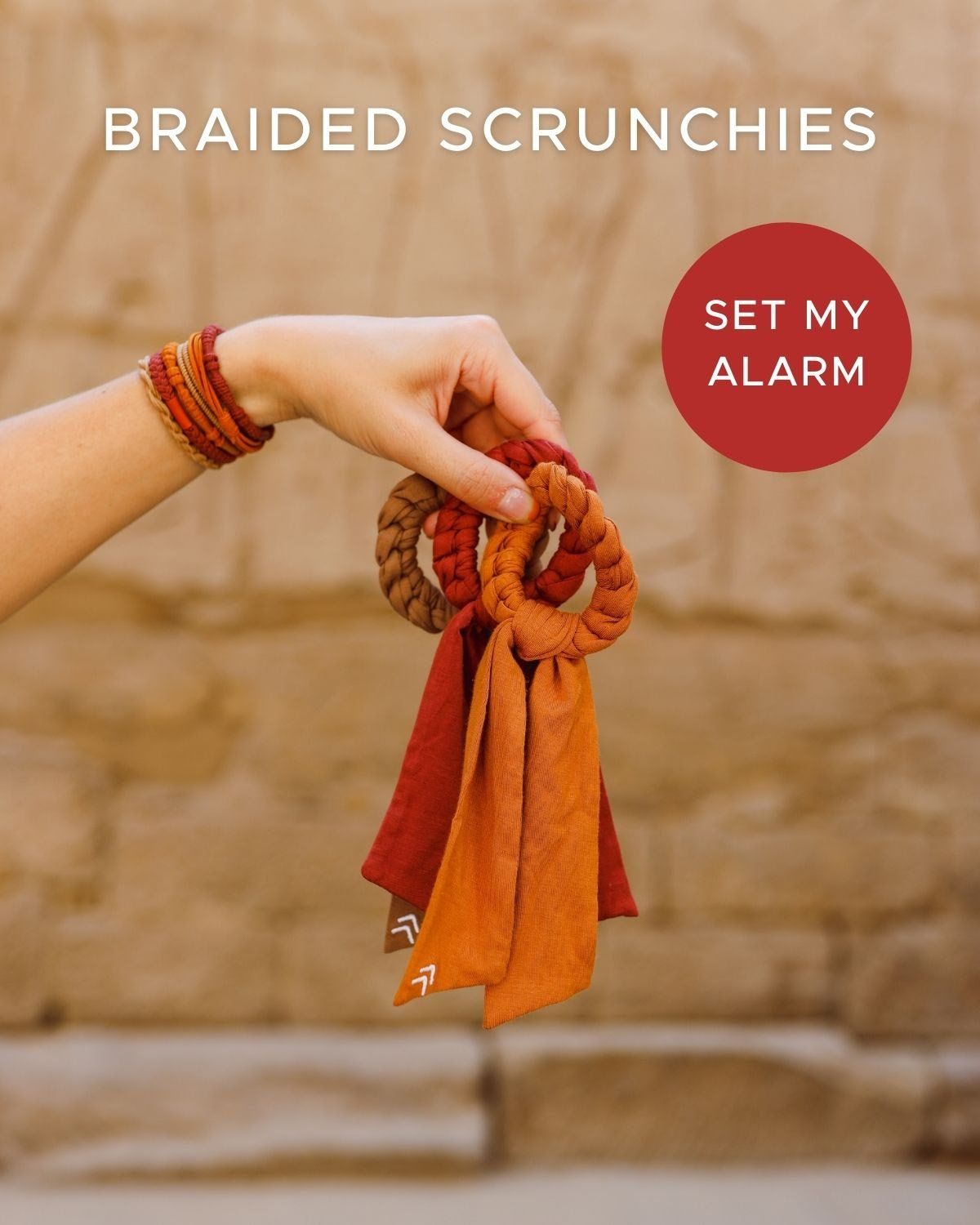 A person is holding a braided scrunchie in their hand