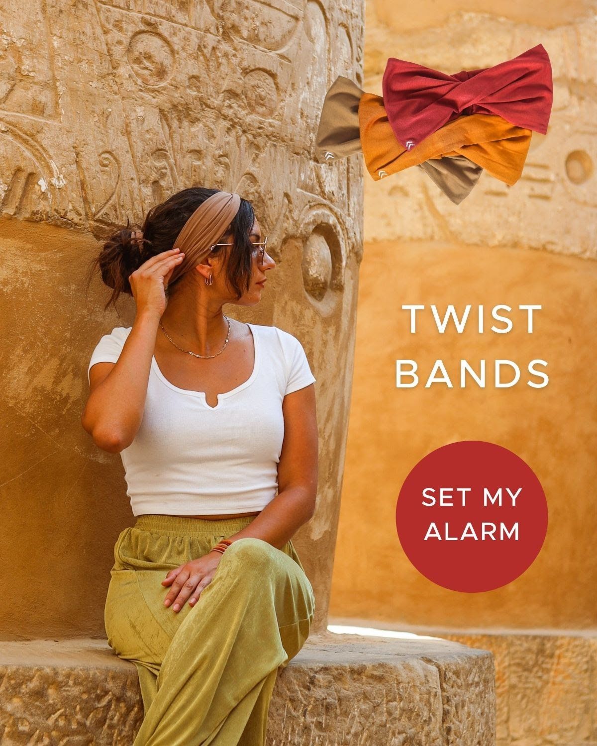 A woman is sitting on a stone wall wearing a headband.