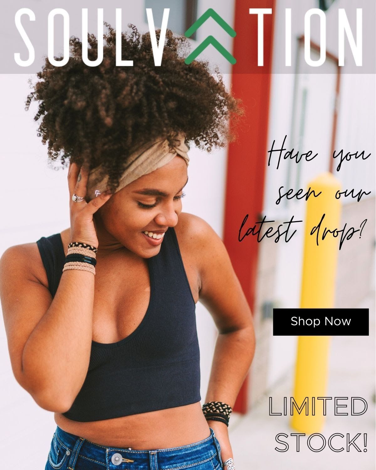 A woman wearing a black crop top and blue jeans is smiling