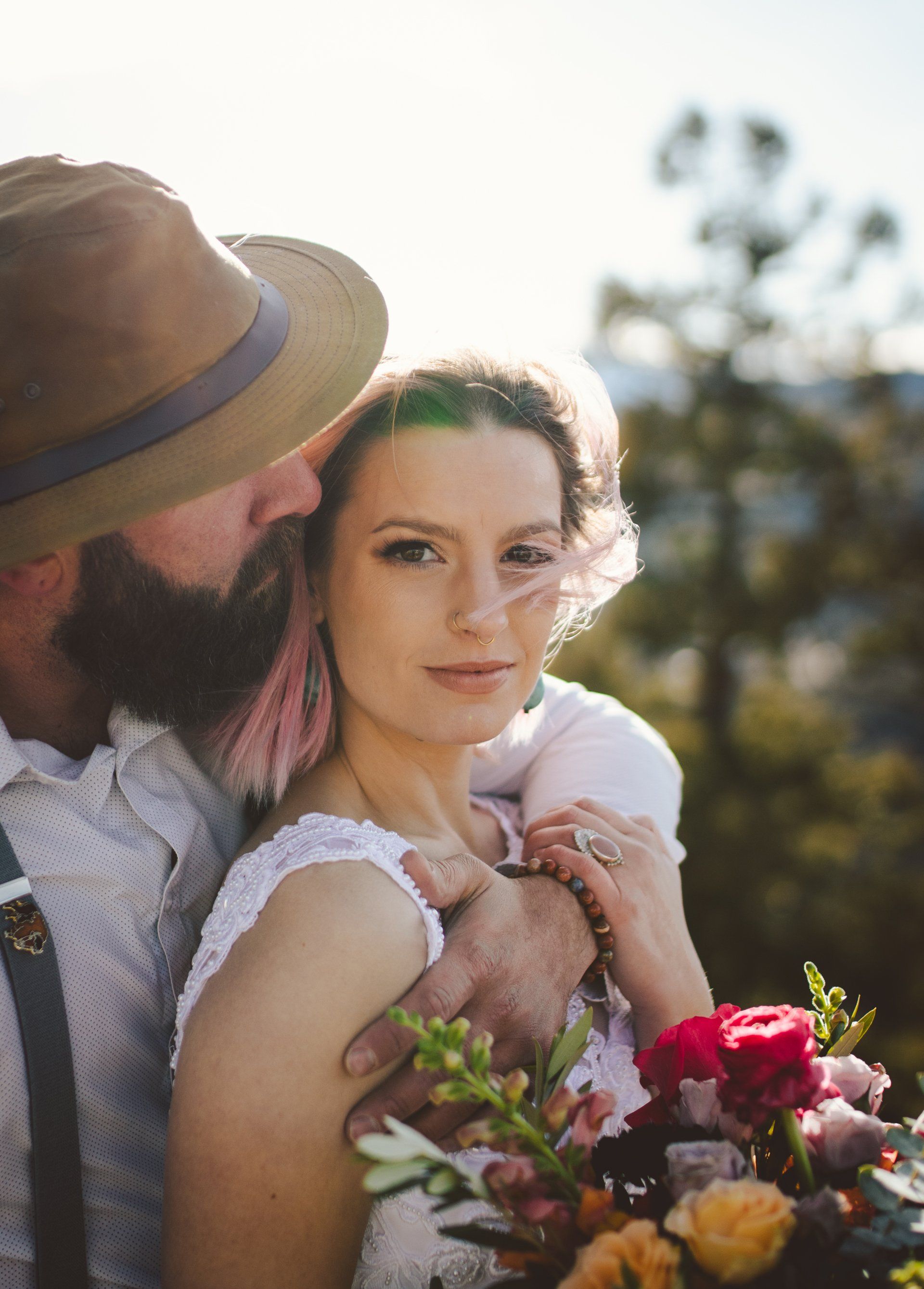 A bride and groom are posing for a picture while the bride is holding a bouquet of flowers.