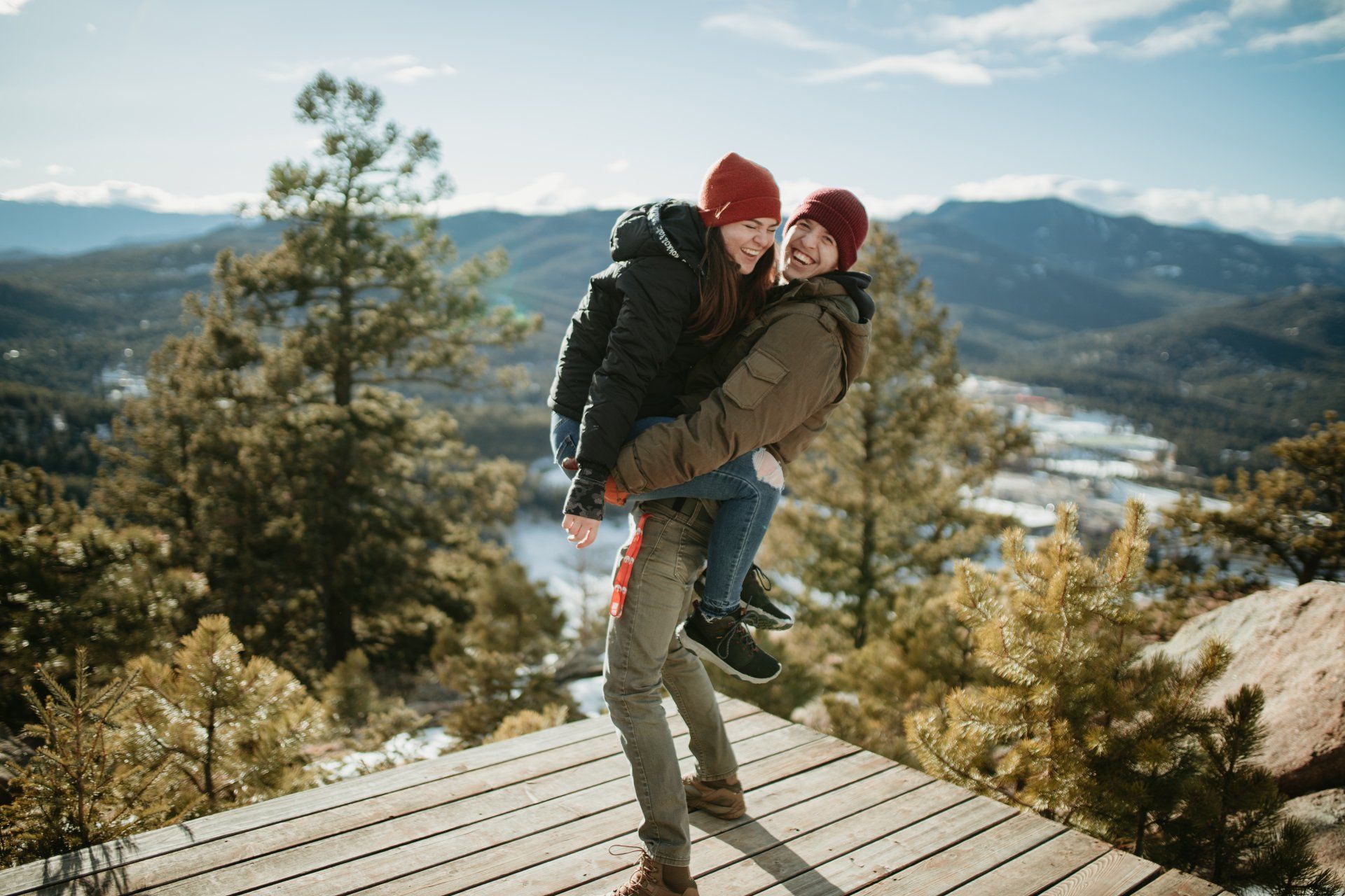 A man is carrying a woman on his back on a wooden deck.