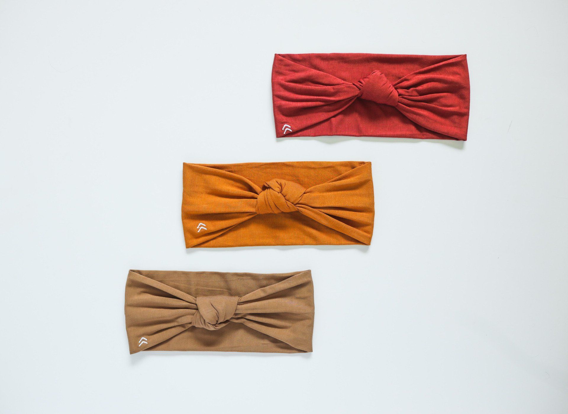 Three different colored headbands are sitting on a white surface.