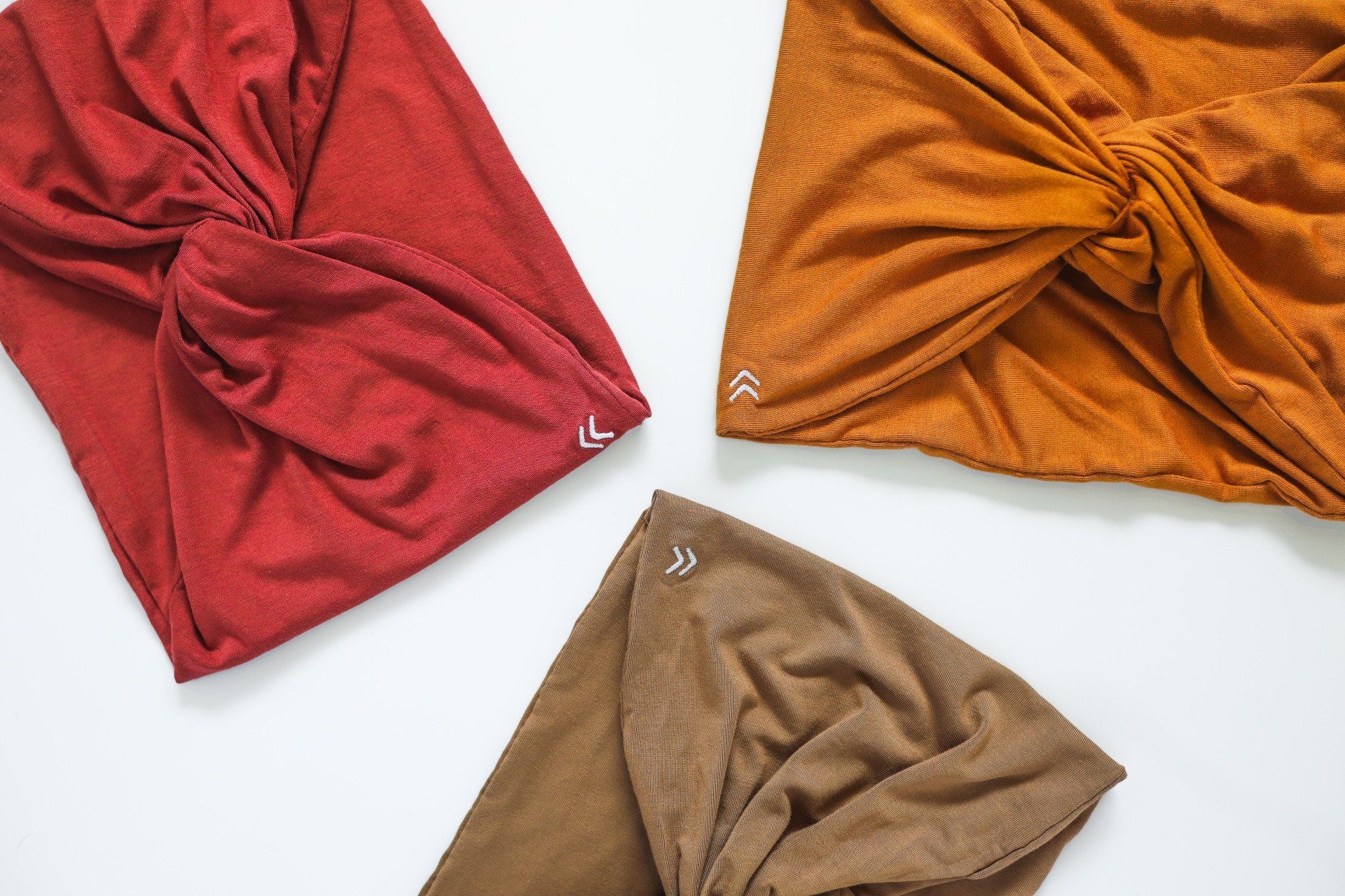 Three different colored turbans are sitting on a white surface.