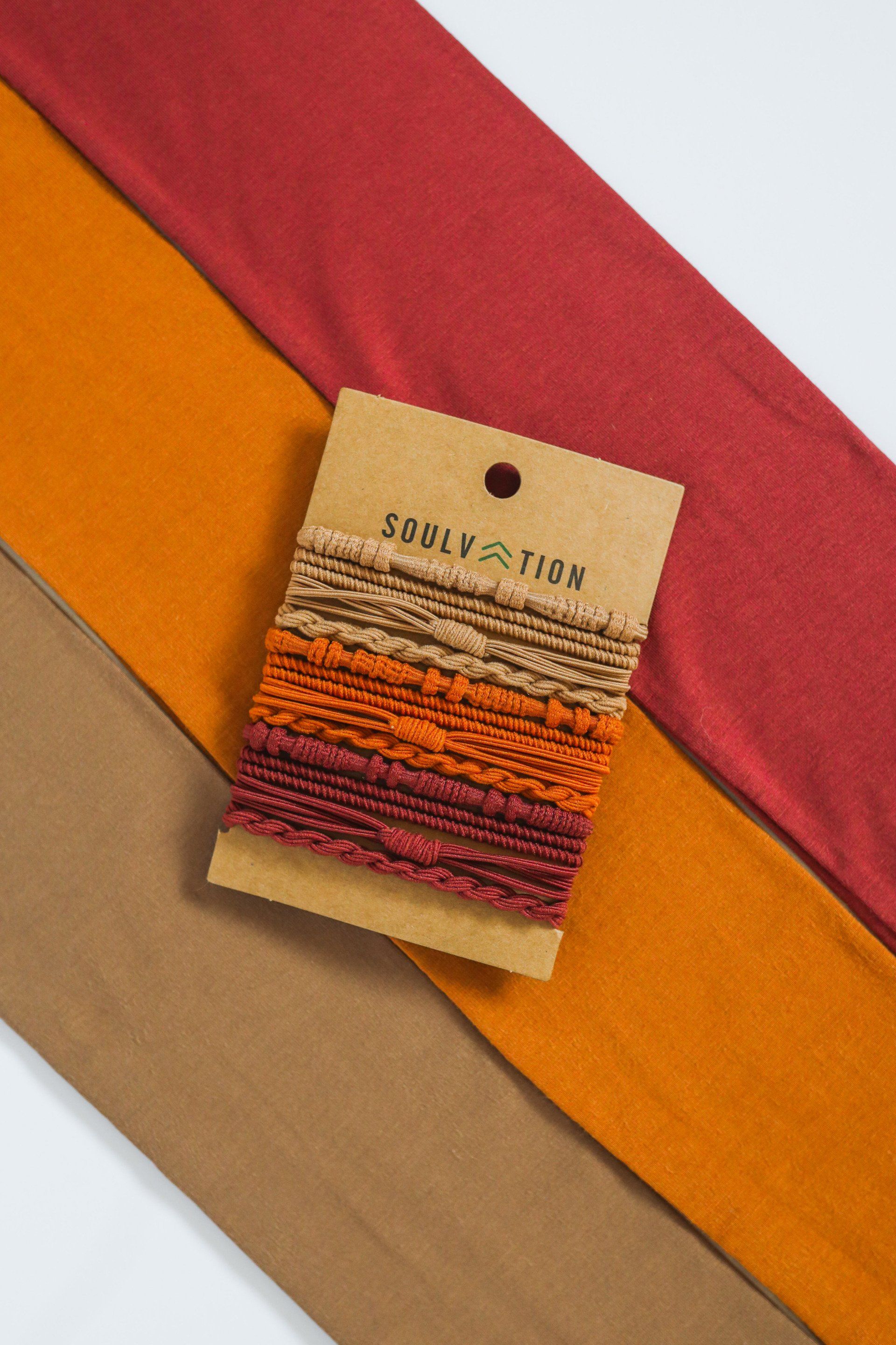 A package of yarn is sitting on top of three pieces of fabric.