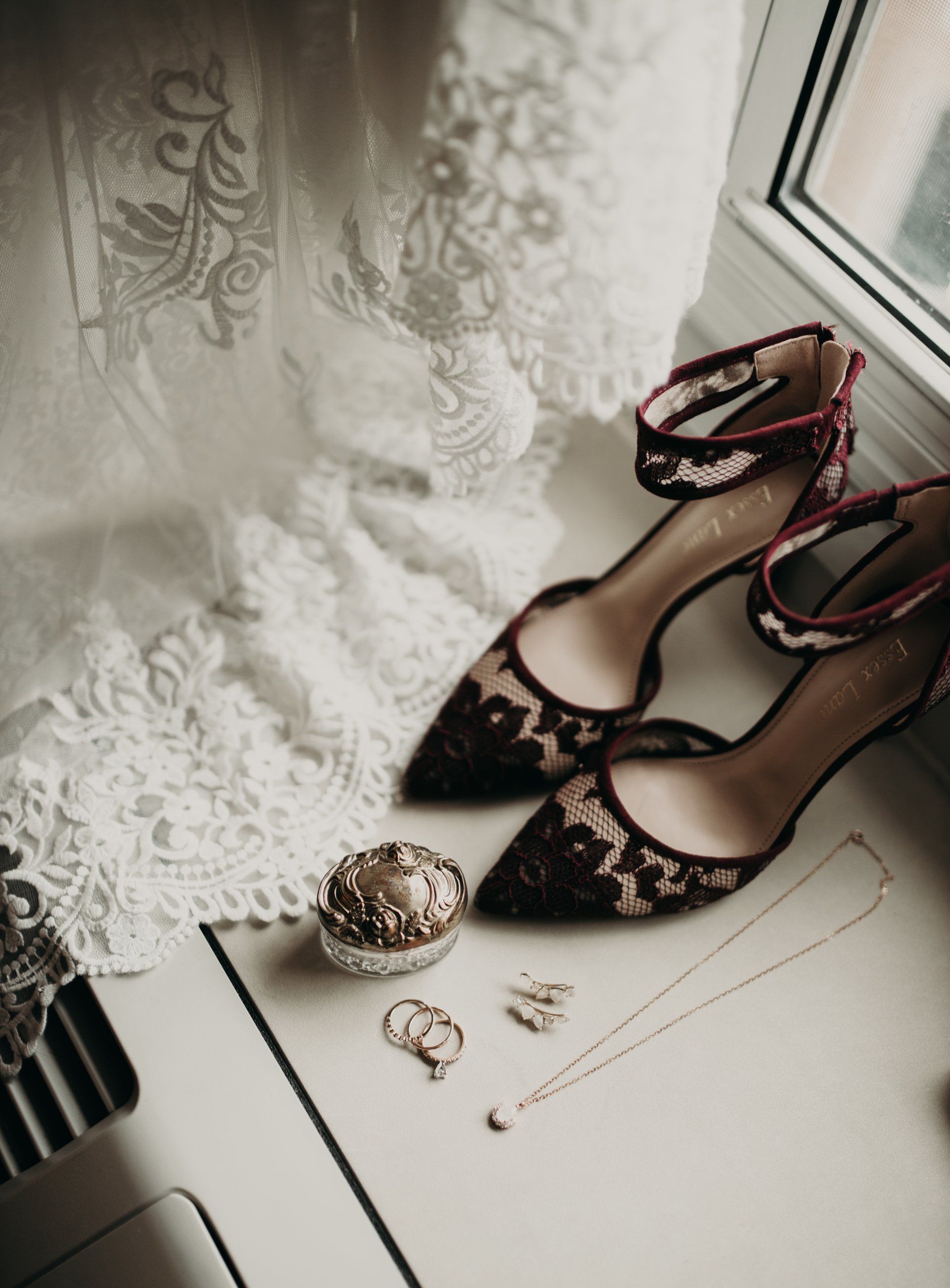 A pair of shoes and jewelry are sitting on a table next to a window.