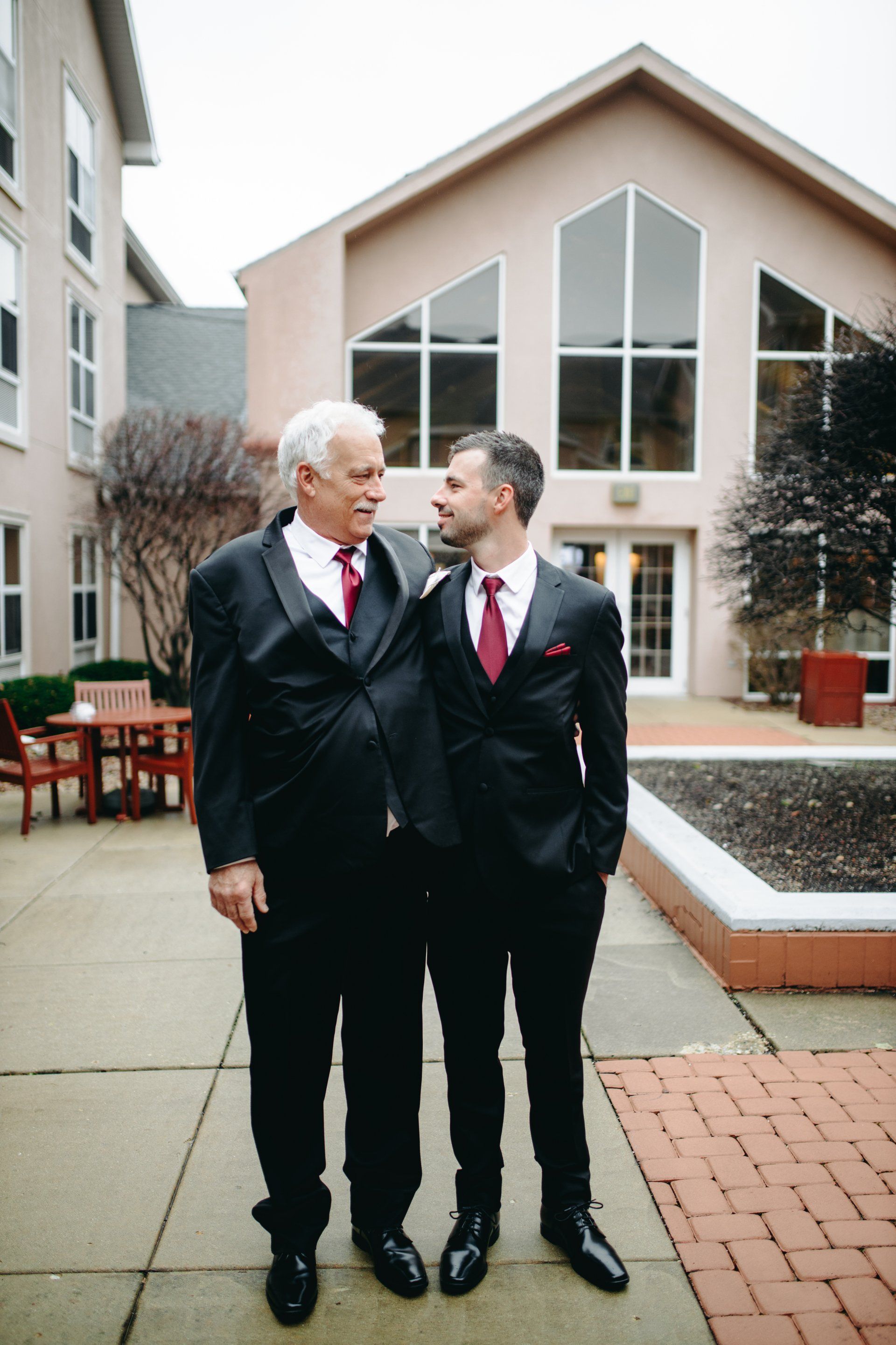 Two men in suits and ties are standing next to each other in front of a building.