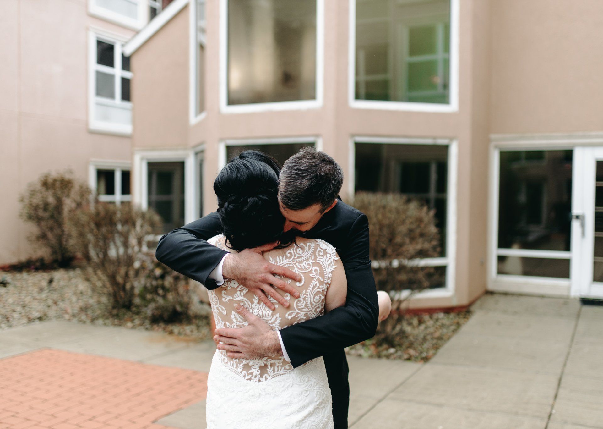 A bride and groom are hugging in front of a building.