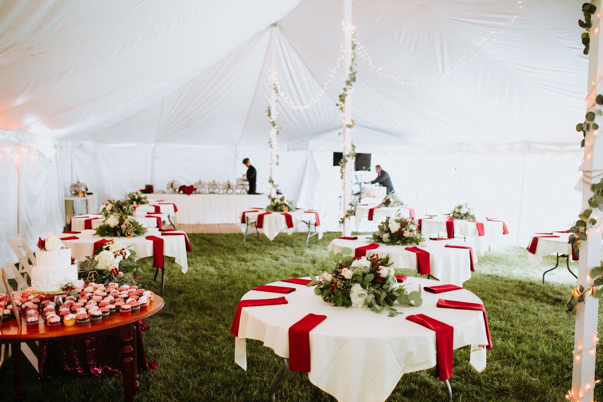 A tent with tables and chairs set up for a wedding reception.