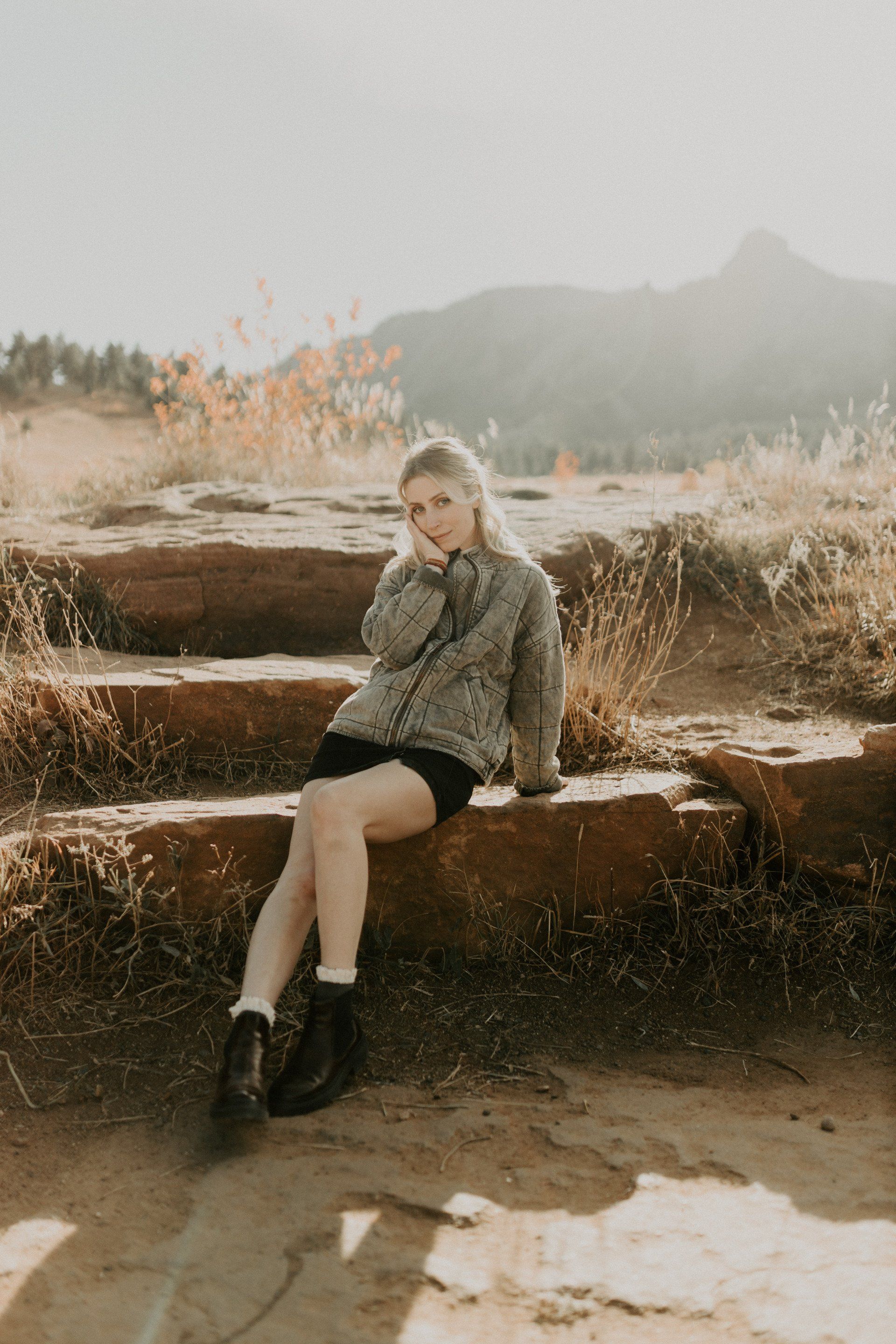 A woman is sitting on a set of stairs with her legs crossed.