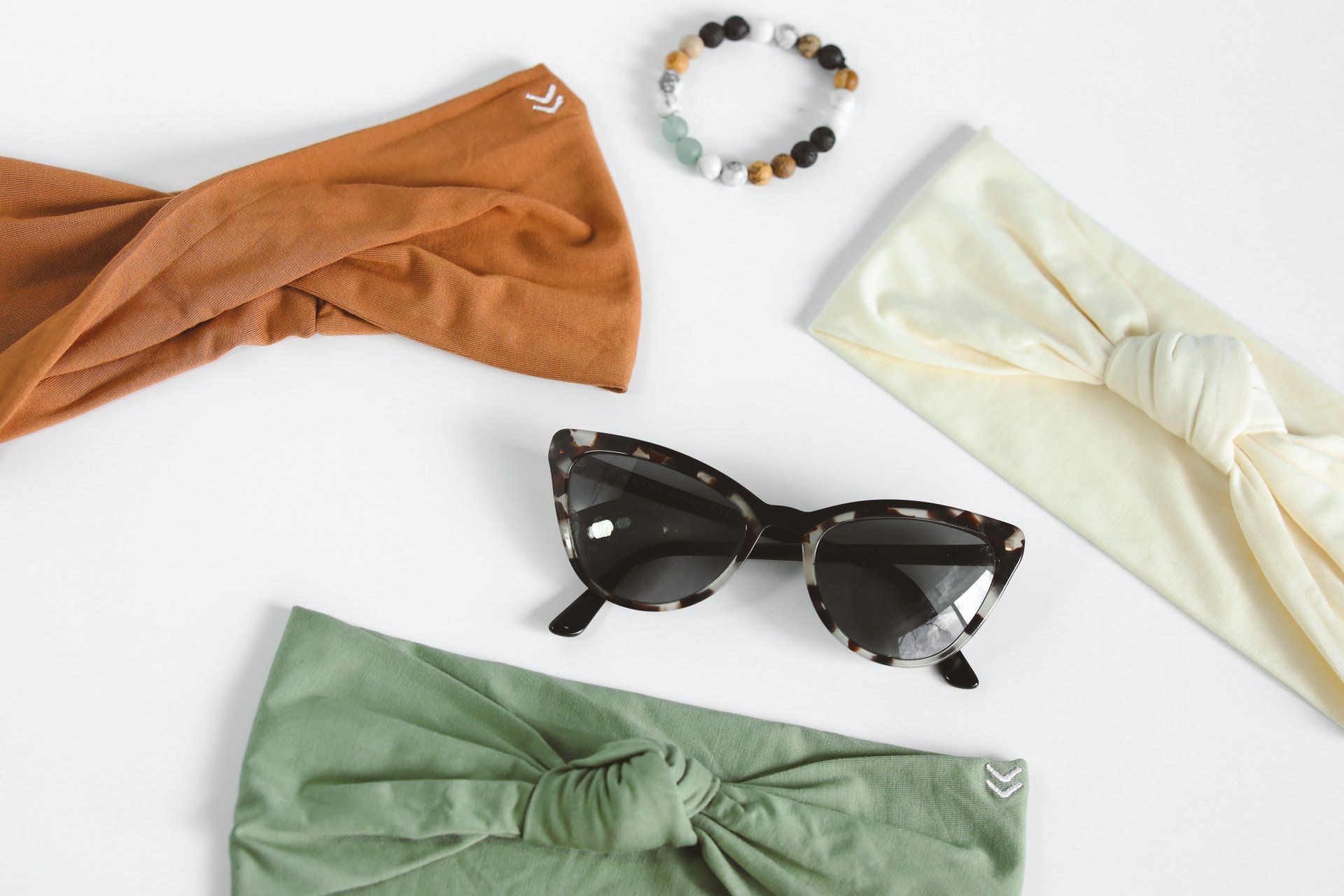 A group of headbands , sunglasses , and a bracelet on a white surface.