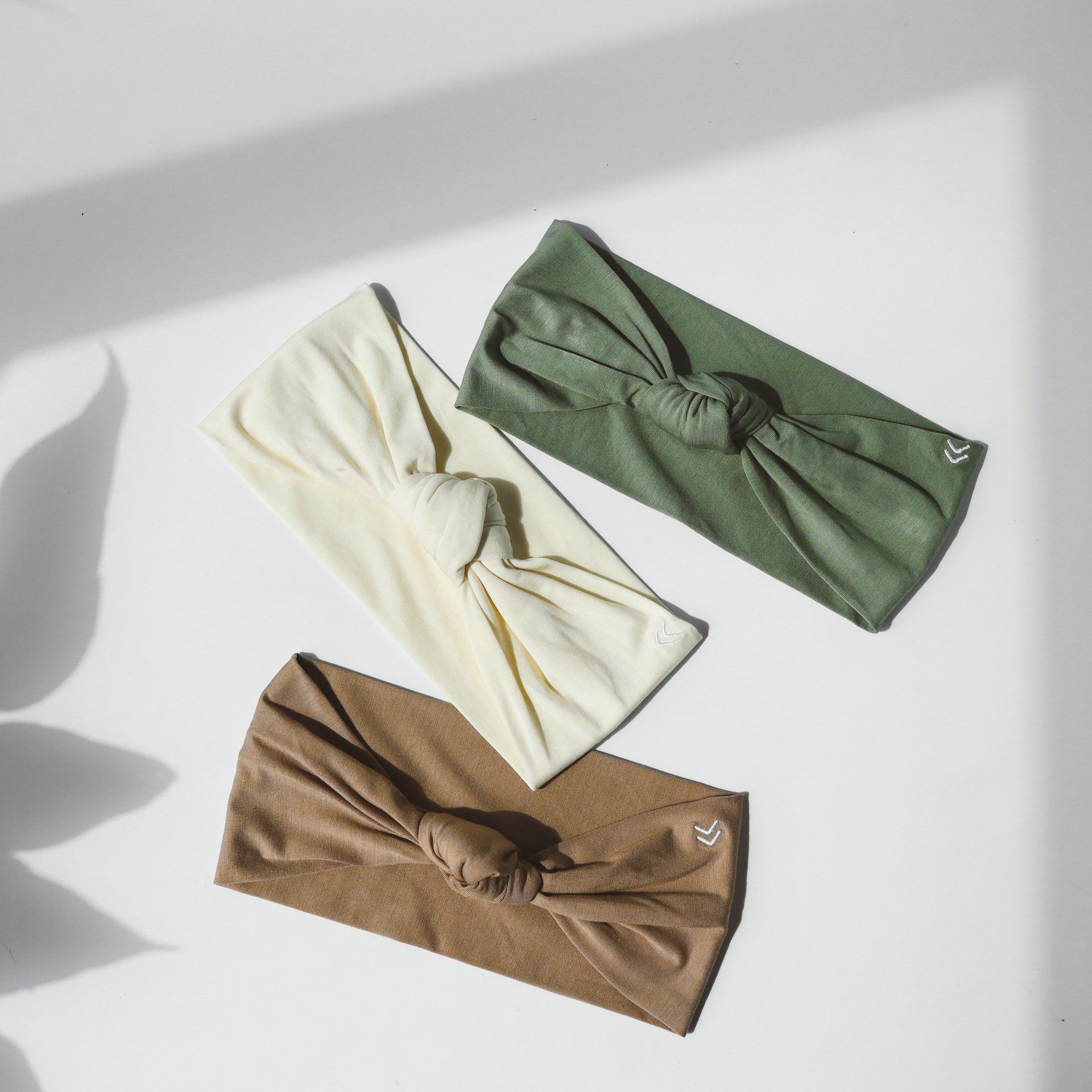 Three different colored headbands are sitting on a white surface