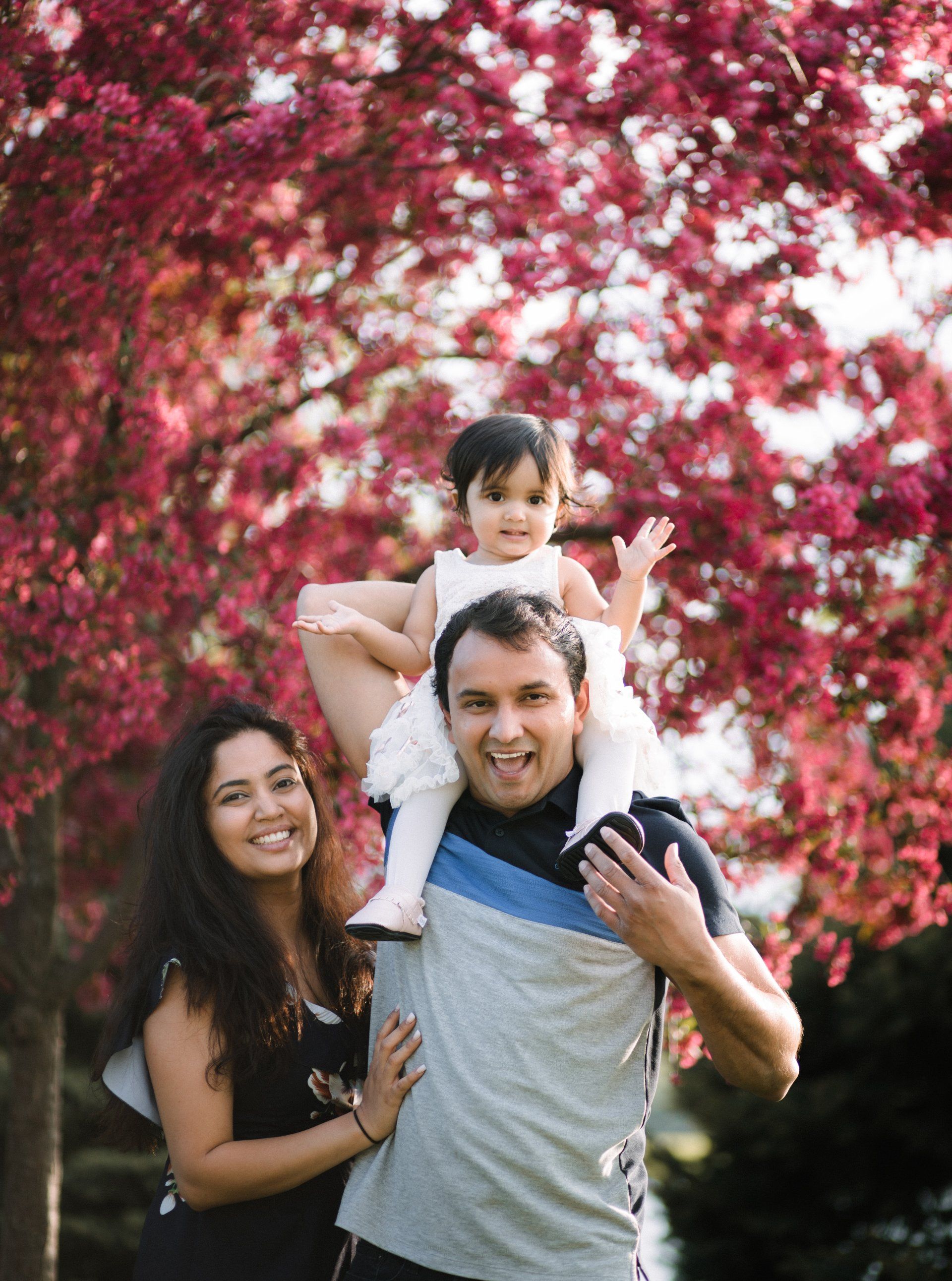 A man and woman are holding a baby on their shoulders.